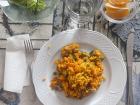 Yellow rice with vegetables, along with some salad and orange