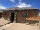 A traditional house that is painted with bright colors, made of clay and has a thatch roof made of straw