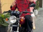 My friend Minh rides a motorbike in a red áo dài with his friend. Wearing a helmet is required in Việt Nam.