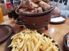 A table with a large serving of fries and chicken in a clay pot