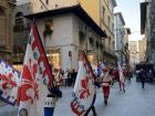 A march where men are holding a version of a Florentine flag with the iconic Florentine symbol, the Giglio