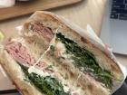 Un sandwich délicieux de focaccia, jambon, épinards, tomates, et stracciatella