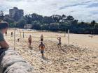 A group of people play beach volleyball on Bondi Beach.
