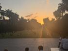 A photo of the National Taiwan University boulevard during sunset. There are students sprawled on the stairs of the library and the greenery