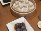 A basket of Xiaolongbao, surrounded by eggplant and wood-ear appetizers